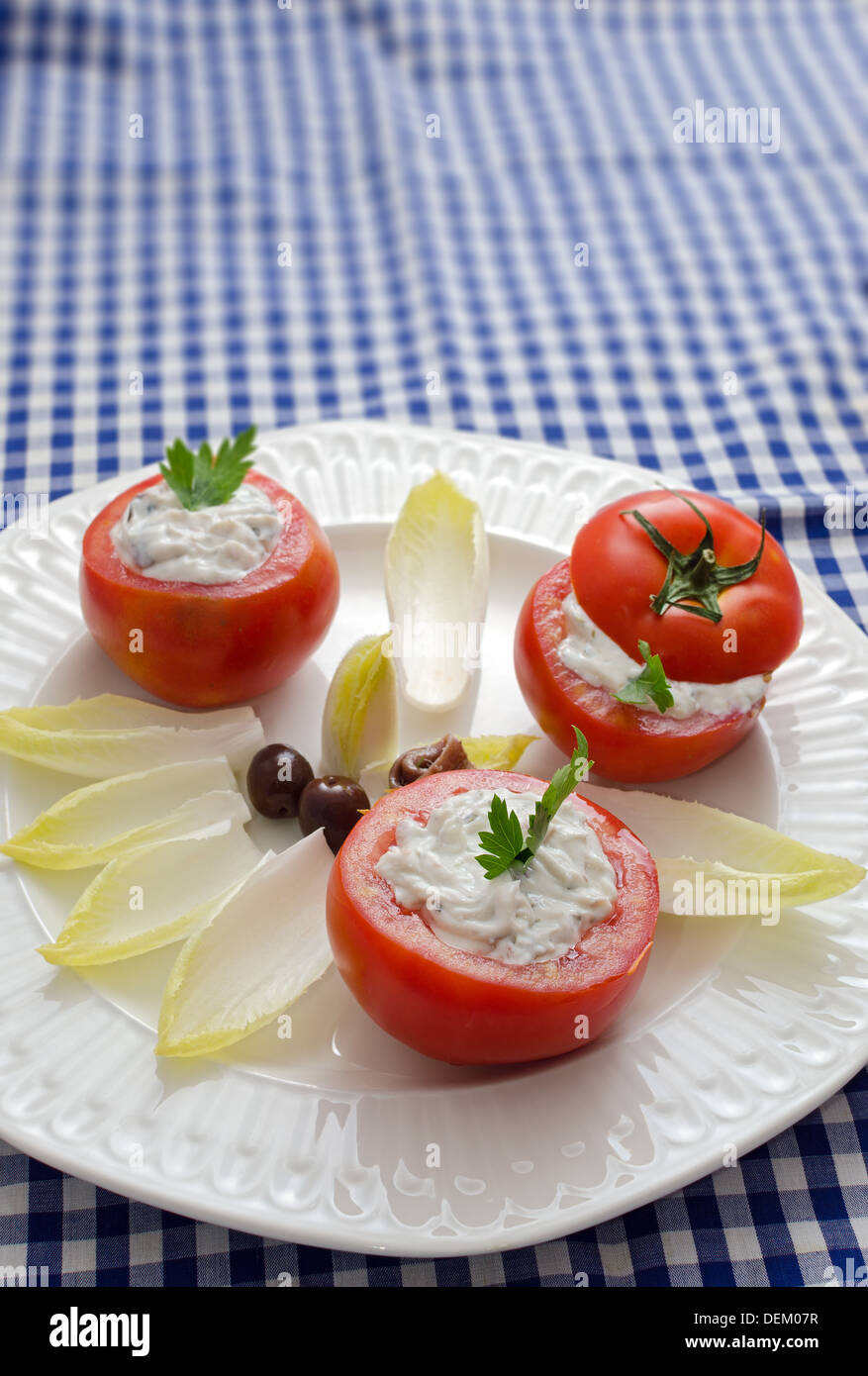 stuffed tomatoes on a white plate on a blue checkered tablecloth Stock Photo