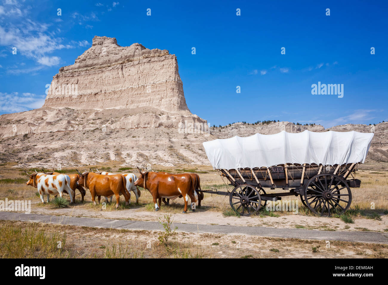 Oxen pulling covered wagon by rock formation, Scott's Bluff National