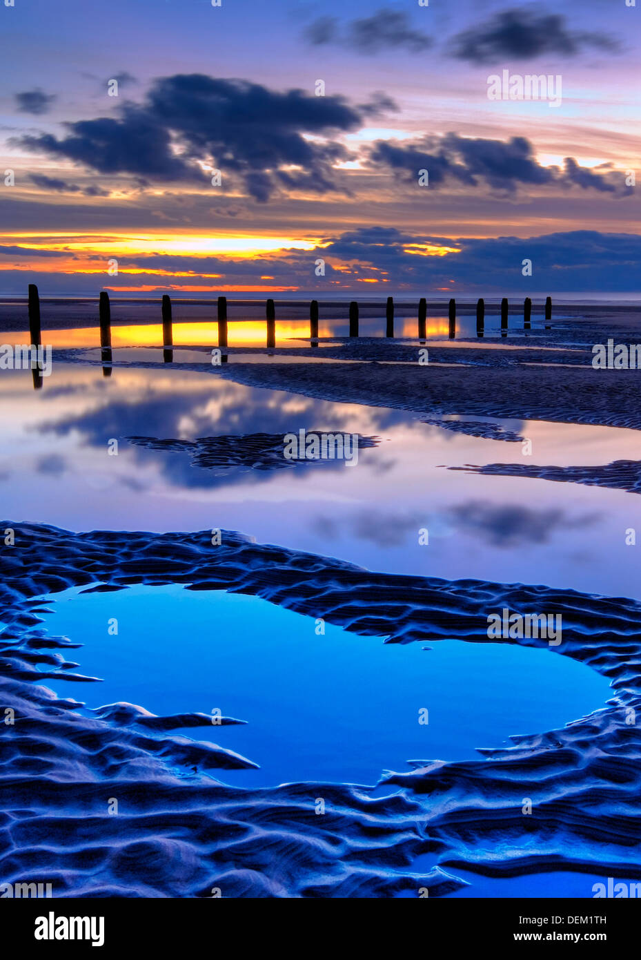 beach and wooden groyne at sunset, with large pools of water and cloud reflections, blackpool, lancashire, england, uk,europe Stock Photo