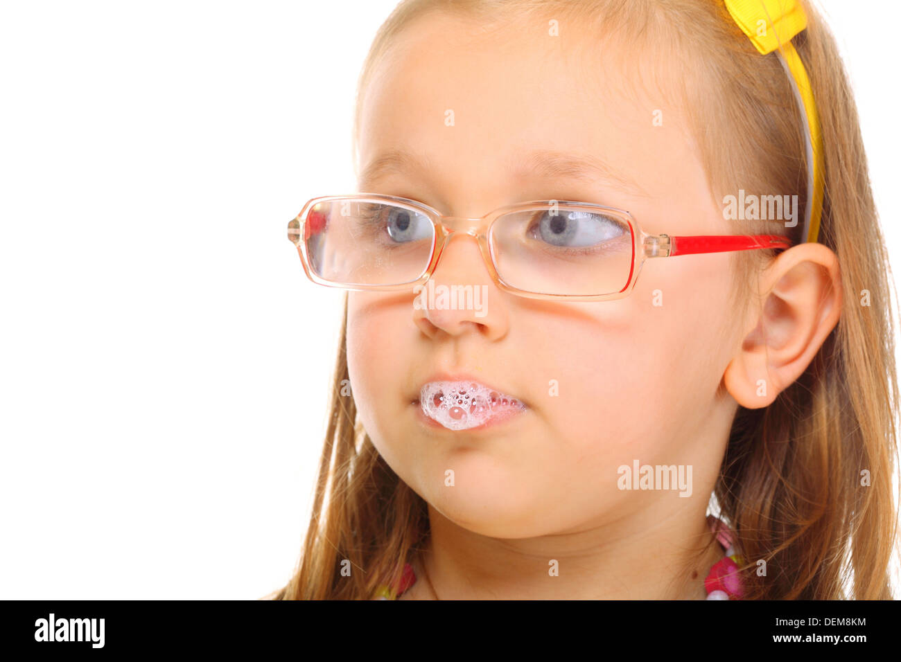 Funny little girl in glasses doing fun saliva bubbles studio shot isolated on white background