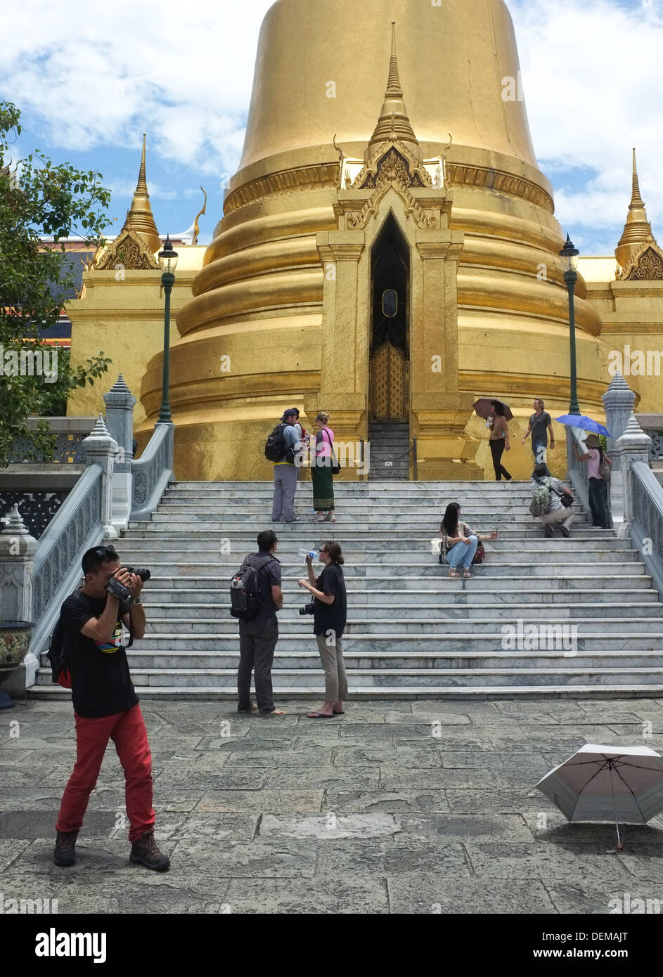 Tourists take photos at the golden Phra Si Rattana Chedi at the Grand Palace complex in Bangkok Stock Photo