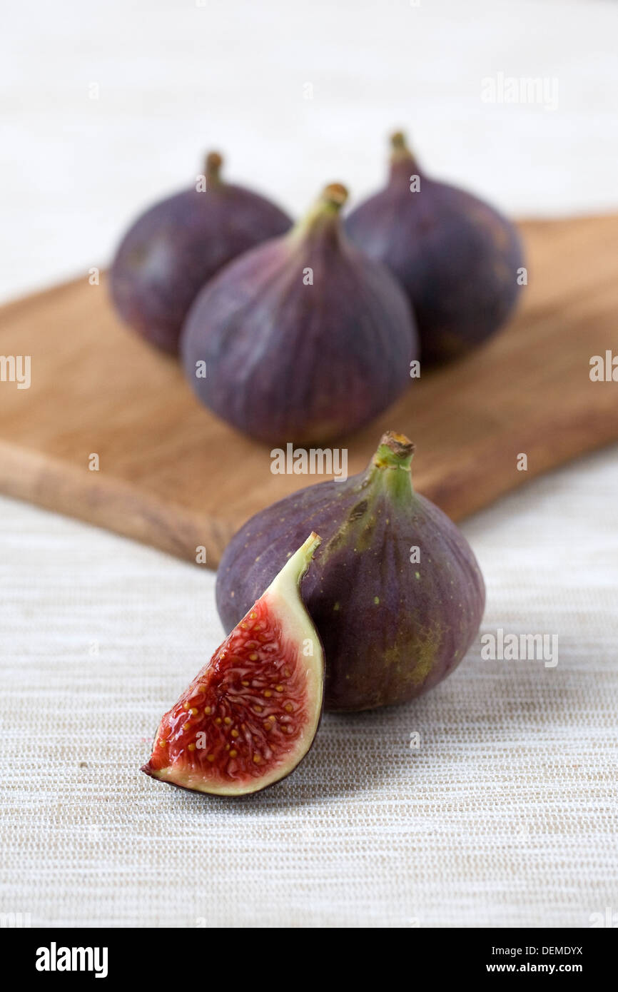 Ficus carica. Five black Bursa figs on a wooden board. Stock Photo