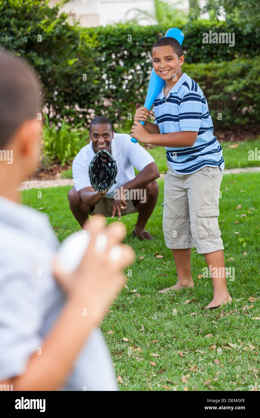 African American family, man, & boy children, father & two sons playing baseball together outside. Stock Photo
