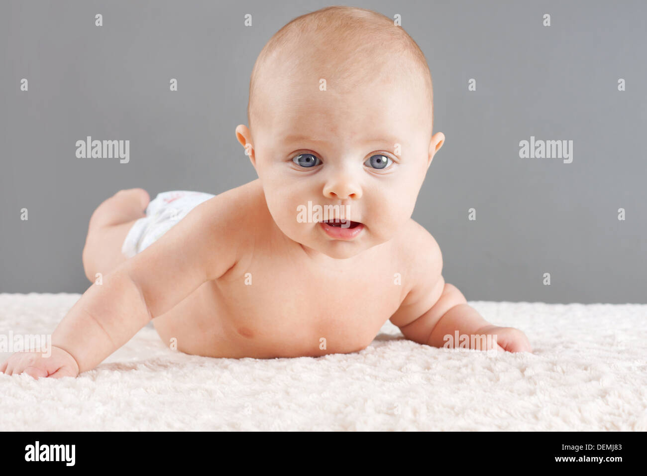 Cute baby on its belly lifting its head looking at camera Stock Photo ...