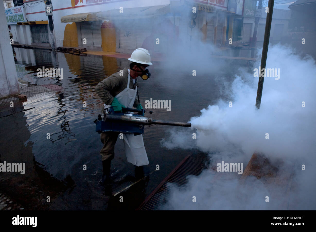 A worker fumigates the streets flooded by the Amazon River to kill the mosquitoes that cause dengue disease. Stock Photo