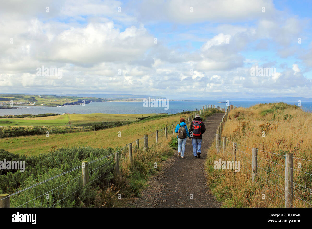 Couple walking along footpath above the Giants Causeway, Northern Ireland. Stock Photo
