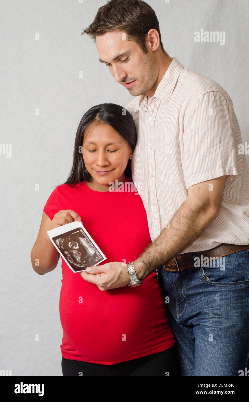 pregnant mixed race couple looking at first scan Stock Photo 60693478