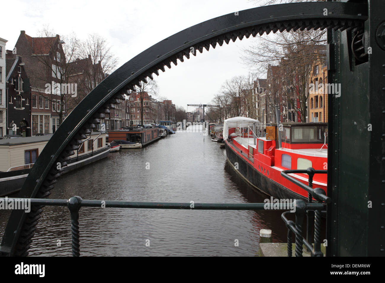 A canal in Amsterdam with house boats framed through the gearing of a draw bridge. Stock Photo