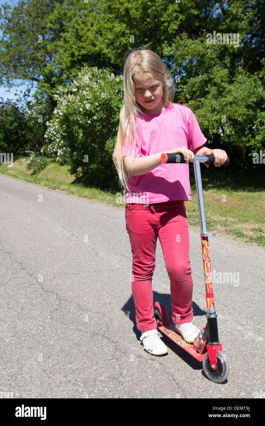 little girl rides a scooter on a rural road Stock Photo Alamy