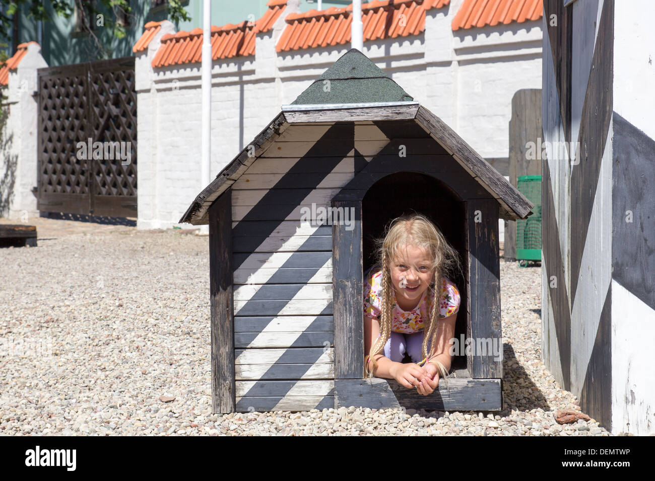 smiling little girl in old wooden dog house Stock Photo