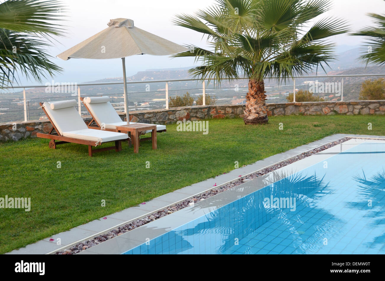 Ready for summer sunbeds by the pool Sunbeds, umbrella, and palm