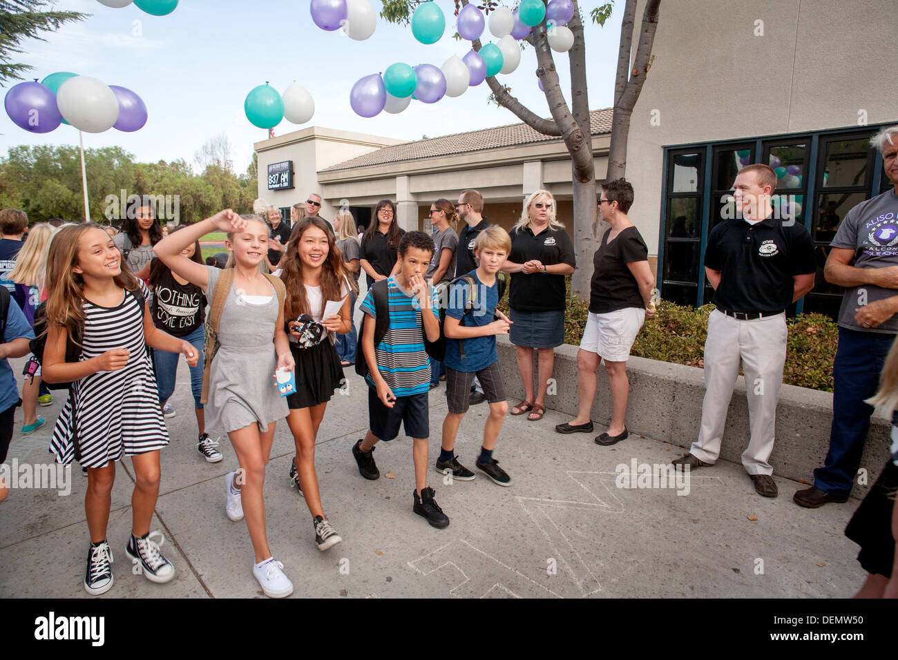 Multiethnic middle school girls greet each other on the first day of school in Aliso Viejo, CA. Note teachers in background. Stock Photo