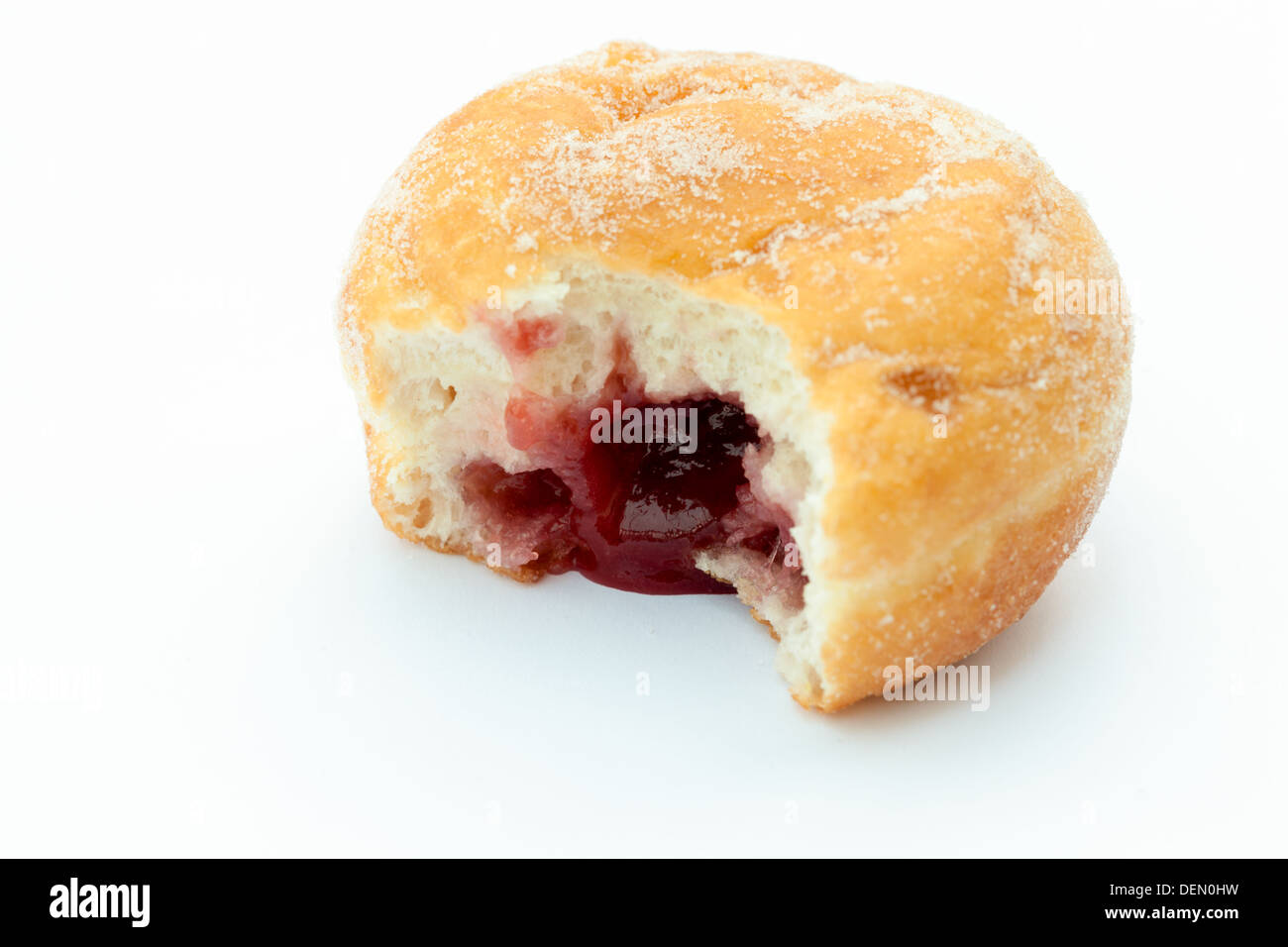 Jam doughnut with a mouthful taken out and jam showing, on a white