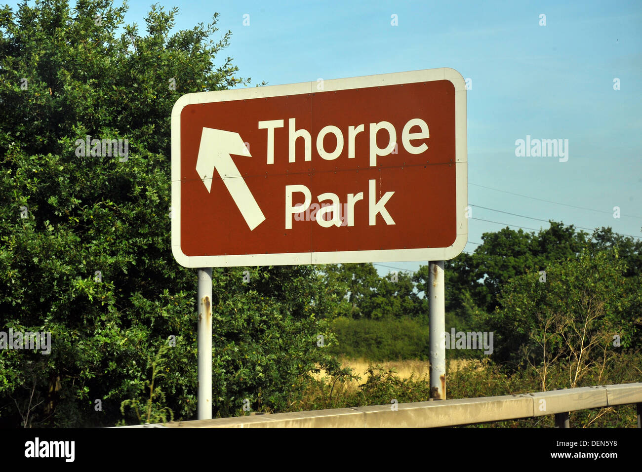 A brown British road sign directing traffic to Thorpe Park. Stock Photo