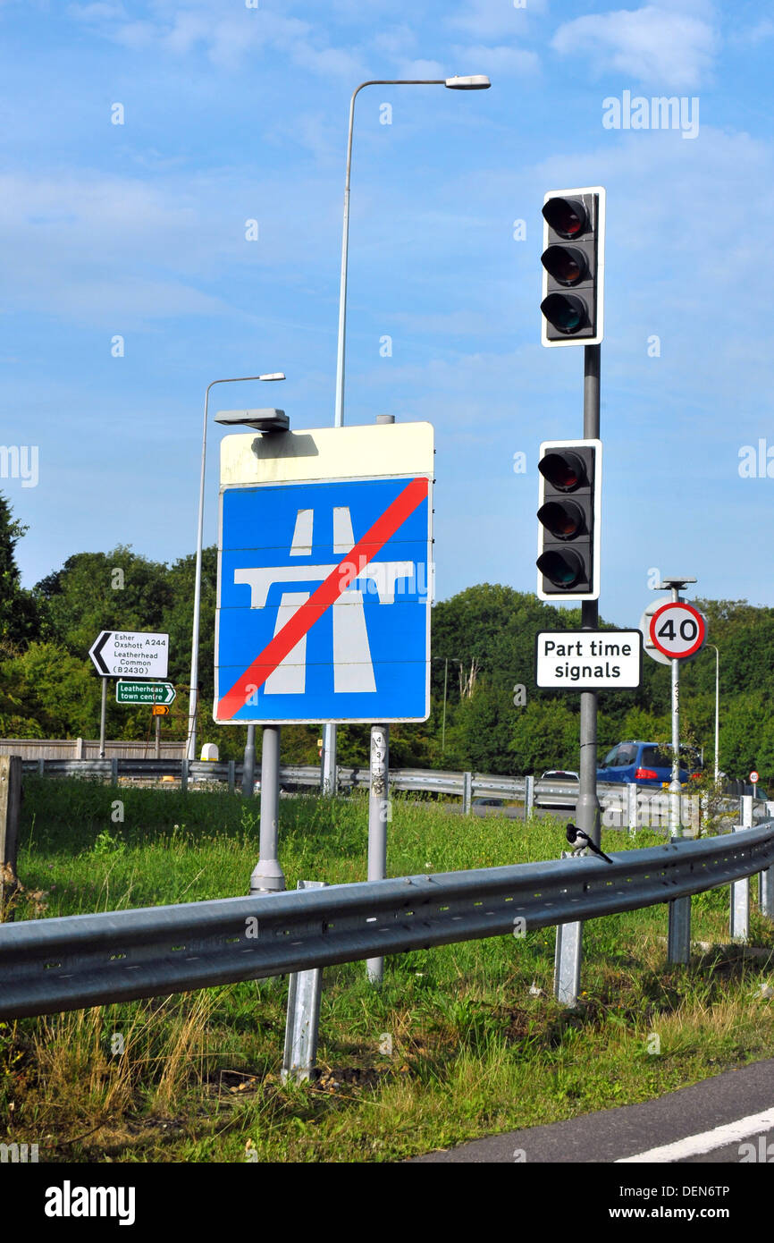 A British road sign indicating the end of the motorway next to traffic lights. Stock Photo