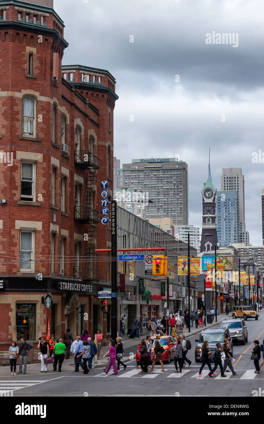 People crossing street at pedestrian crossing and Starbucks Coffee shop - cnr of Yonge street and College street, Toronto Stock Photo