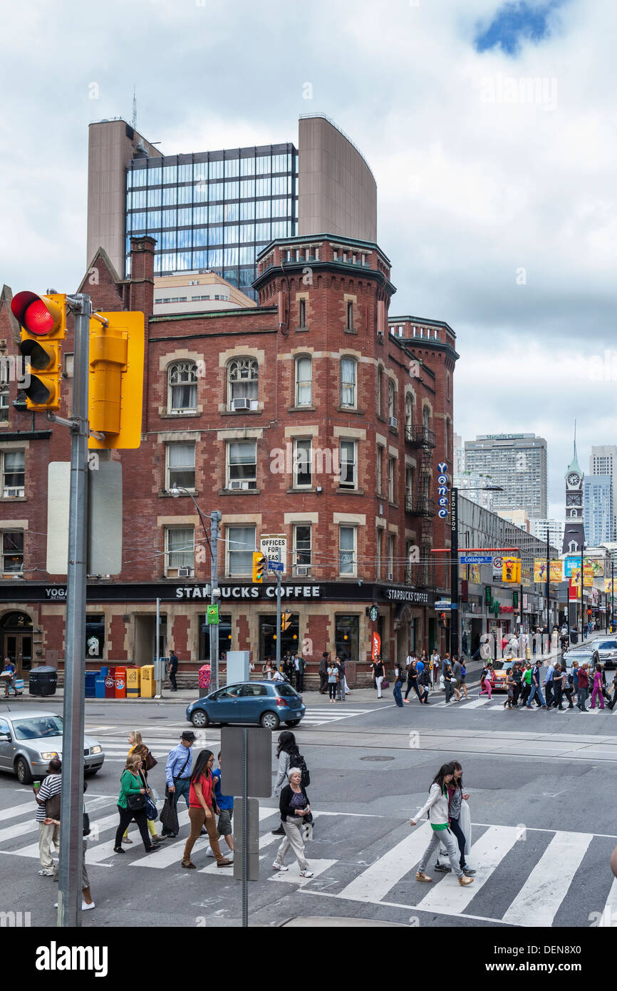 People crossing street at pedestrian crossing and Starbucks Coffee shop - cnr of Yonge street and College street, Toronto Stock Photo