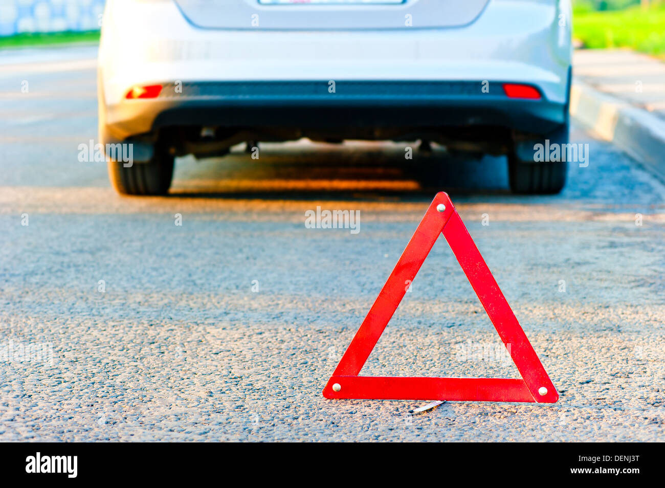 red warning triangle and a car pull over to the side of the road Stock Photo
