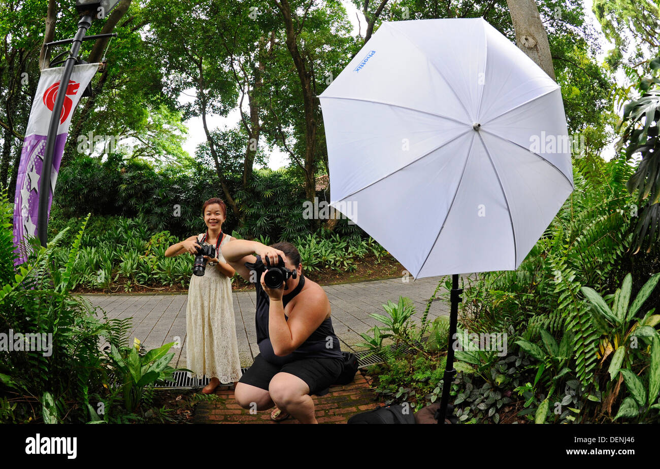 Two female photographers taking photographs with electronic flash and diffused umbrella. Stock Photo