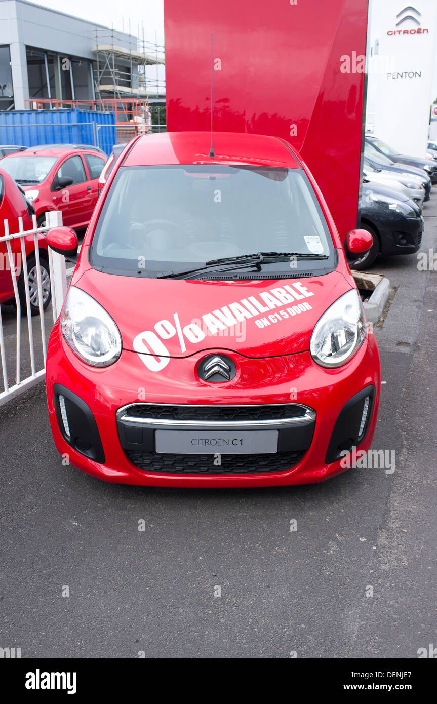 New red Citroen C1 car for sale at UK car dealer with 0% finance offer in white lettering stickers on bonnet Stock Photo