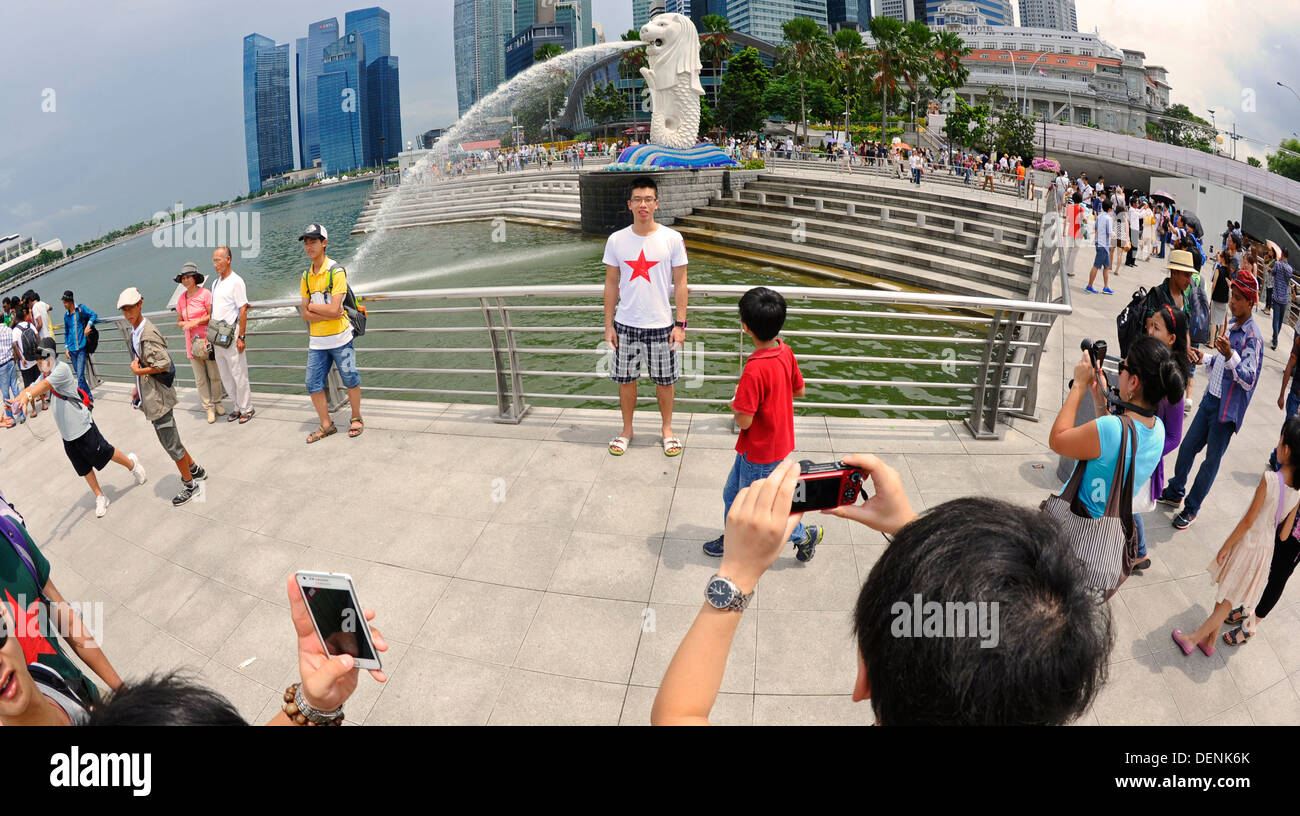 Tourist posing for photographs at the Merlion park in Singapore Stock ...