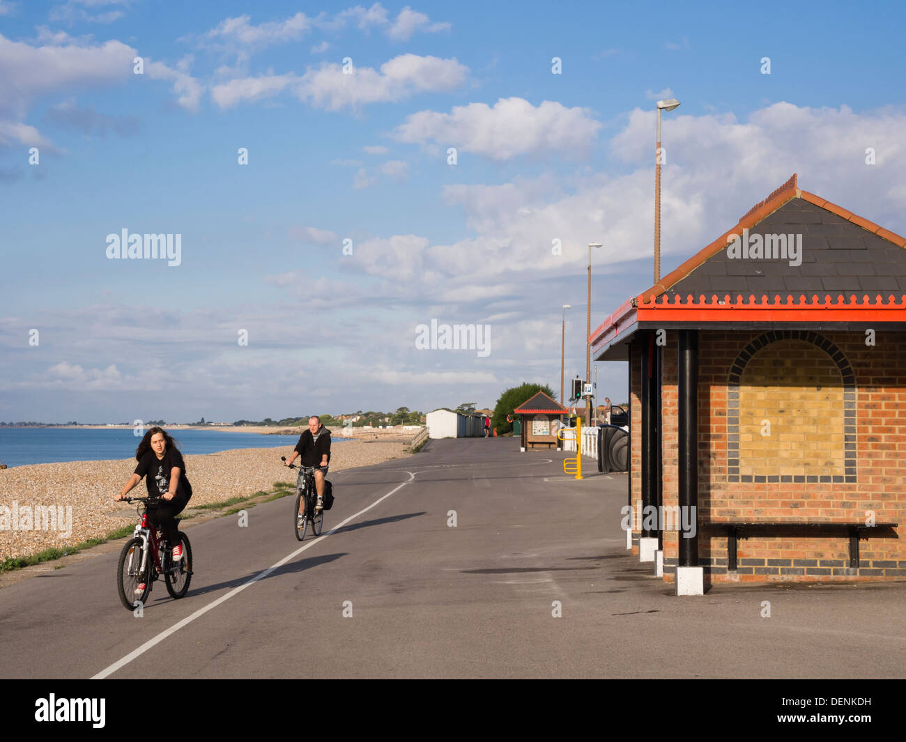 Two people cycling along cycle track for exercise on a seafront promenade in Aldwick, Bognor Regis, West Sussex, England, UK, Britain Stock Photo