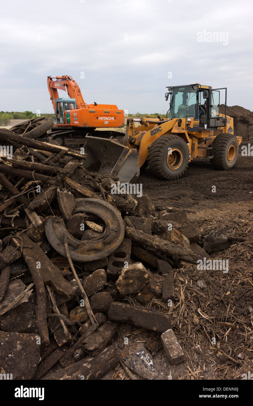 Front end loader poised at the edge of a rubble pile. Stock Photo
