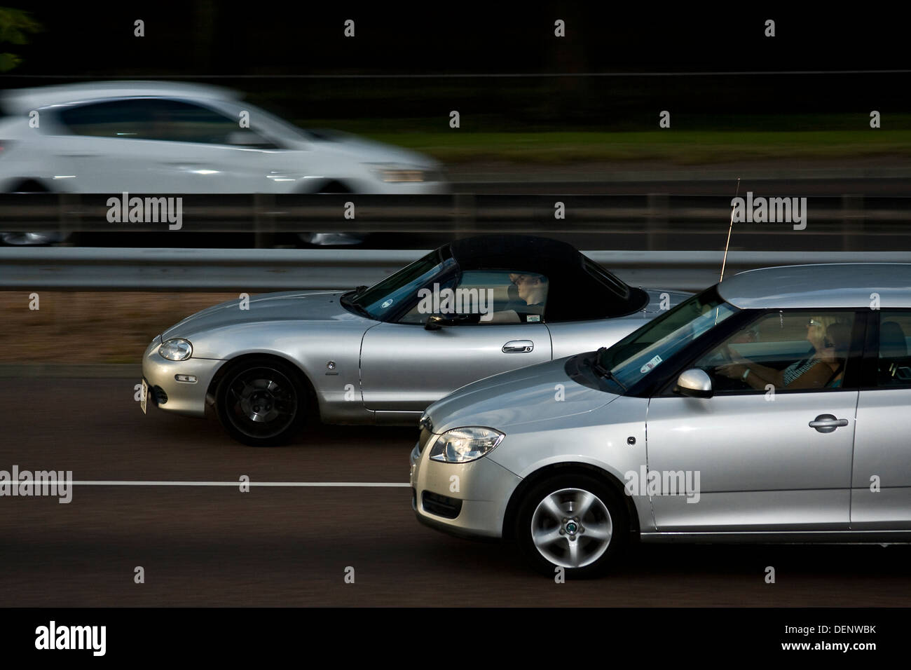 Rear sync flash technique used to capture three cars travelling along the Dundee Dual Carriageway late in the evening, UK Stock Photo