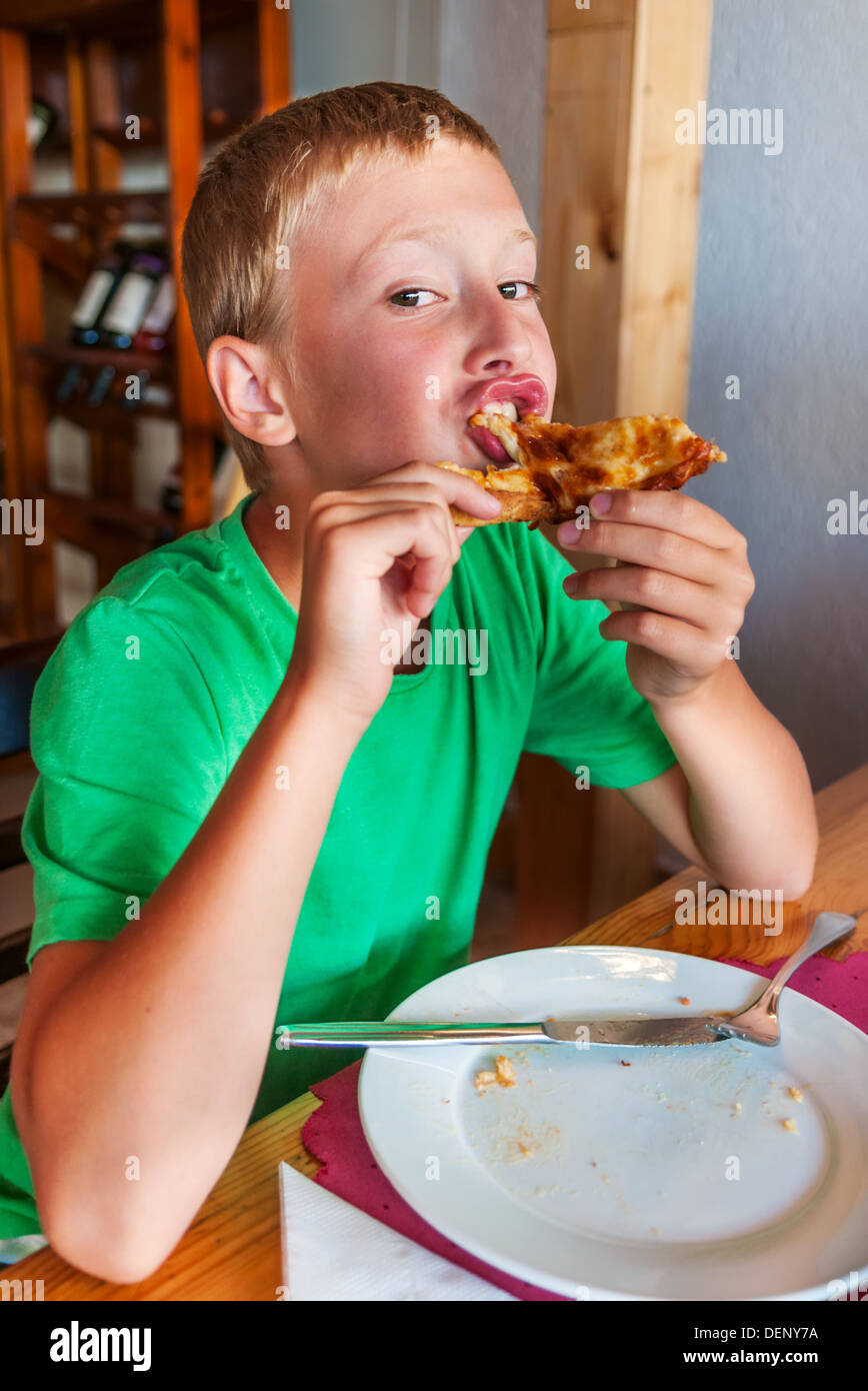 Young boy eating pizza at restaurant Stock Photo