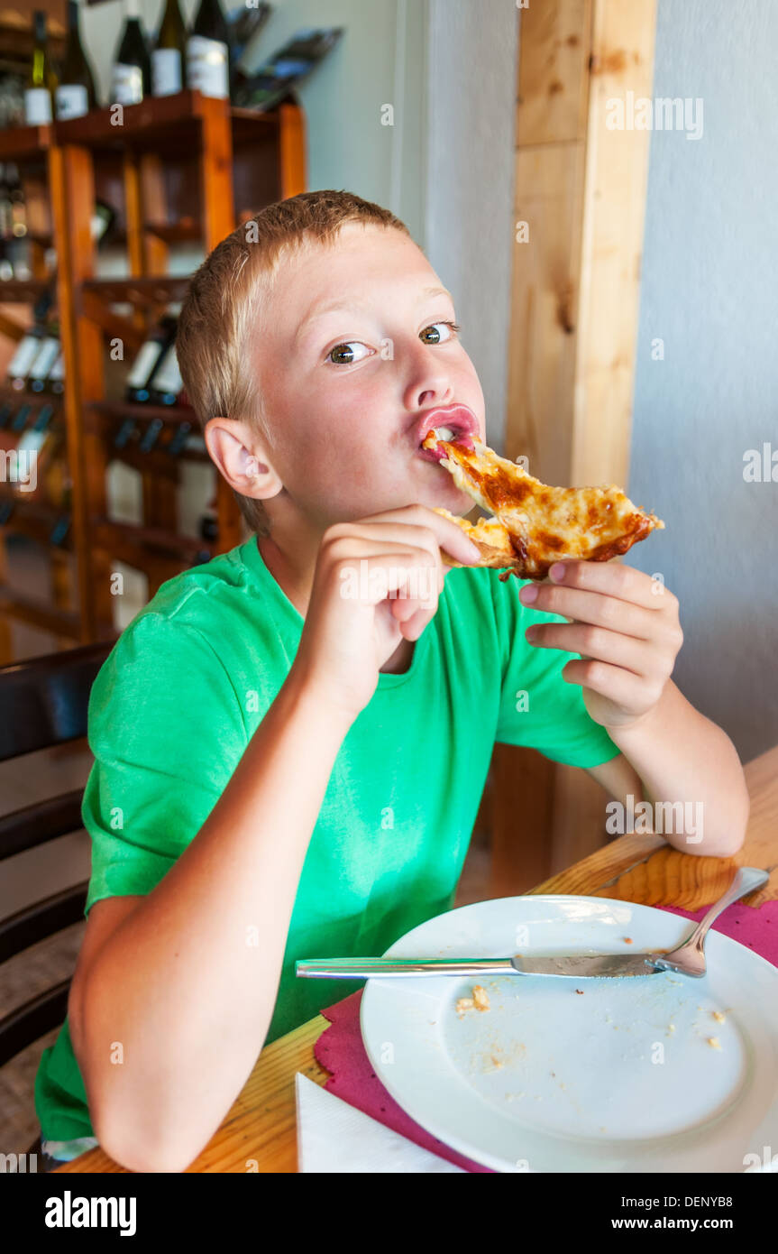 Young boy eating pizza at restaurant Stock Photo