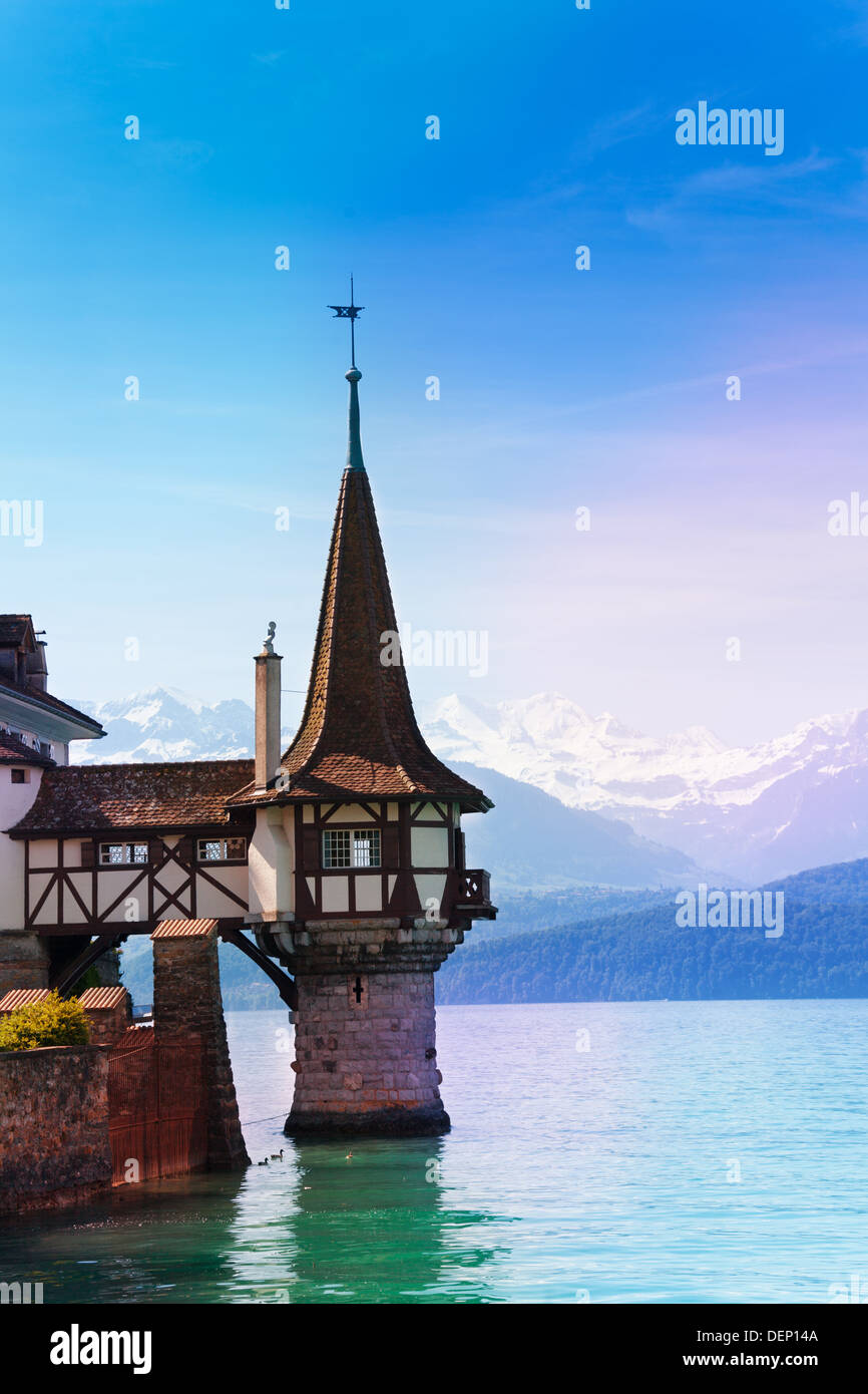 Beautiful famous tower of Oberhofen castle in the Thun lake with mountains on background in Switzerland, near Bern  Stock Photo