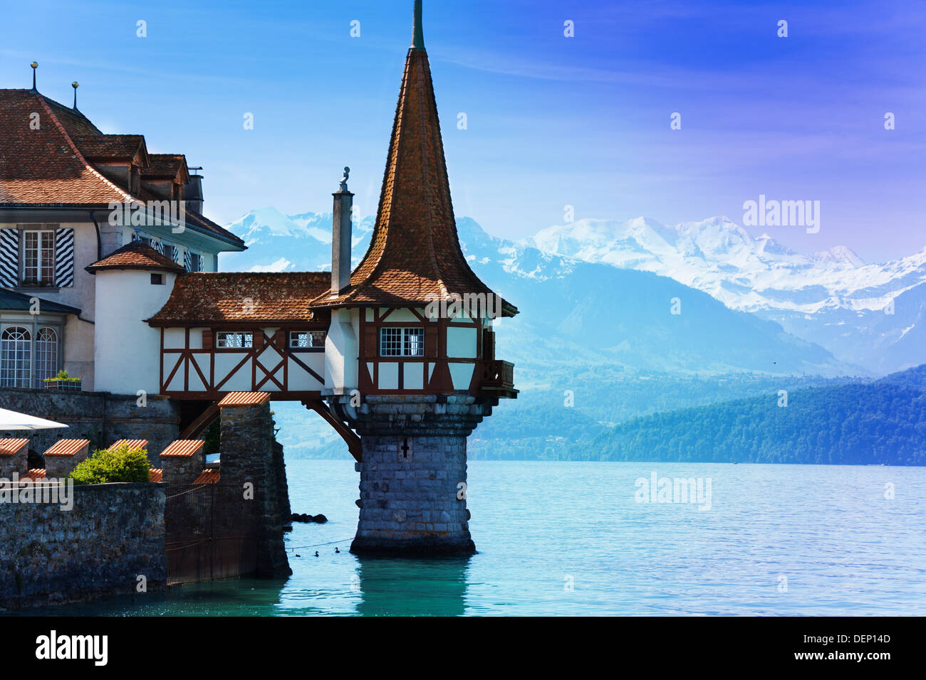 Beautiful little tower of Oberhofen castle in the Thun lake with mountains on background in Switzerland, near Bern  Stock Photo