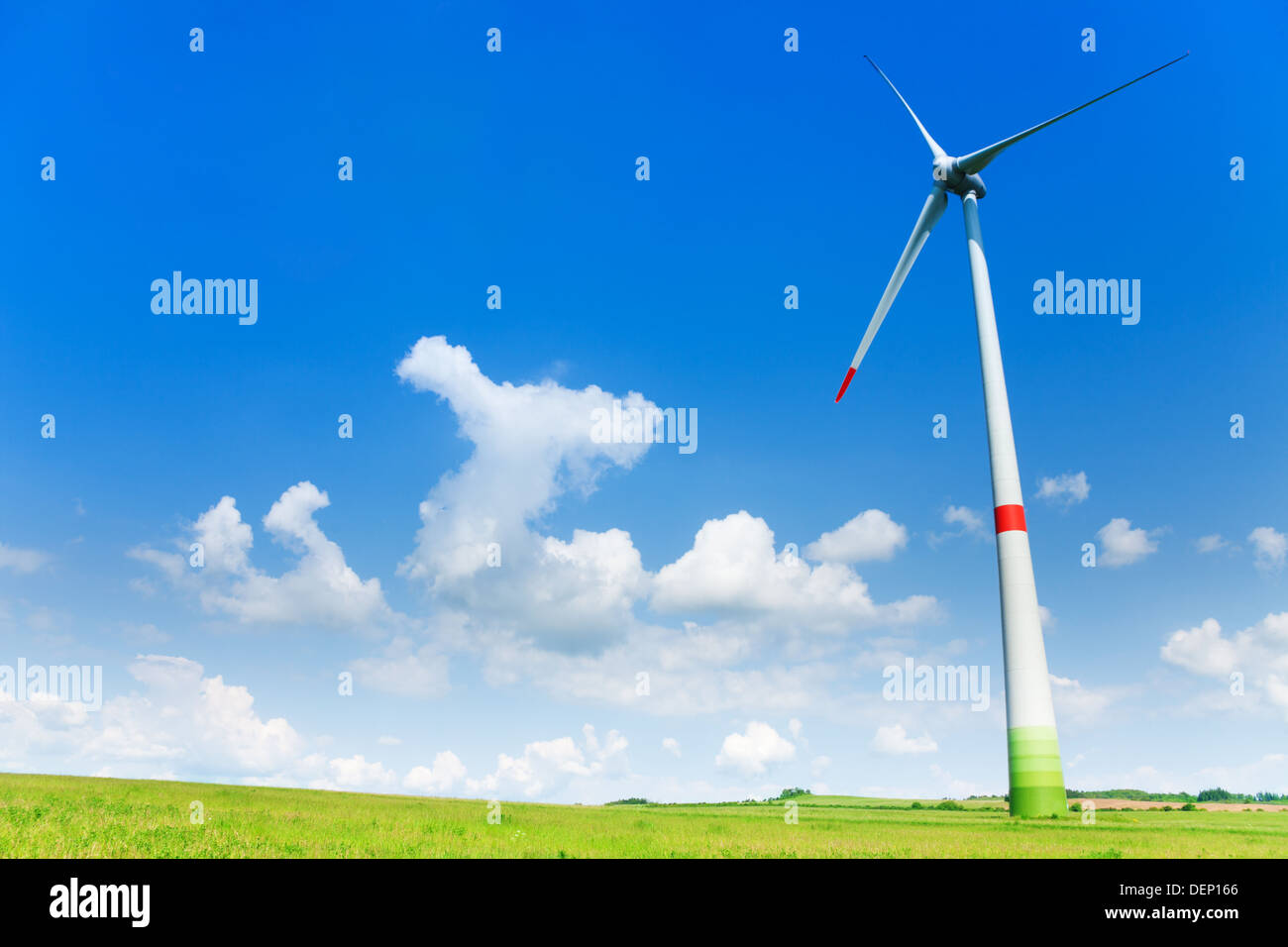 Wind turbine in the field with clouds in the sky on bright sunny day ...