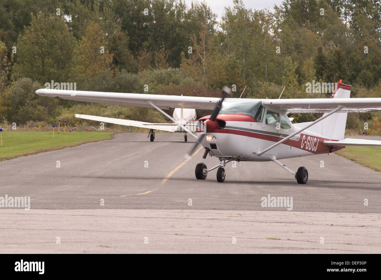 2 planes on runway at Kawartha Lakes Airport. One about to take off the other has just landed. Stock Photo