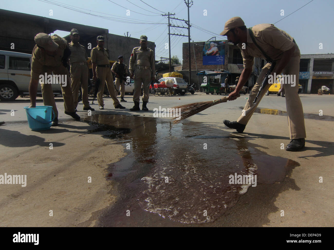 Srinagar, Kashmir. 23rd Sep, 2013. indian policeman wash the blood stained road where two CISF were shot and killed at close range at Iqbal Park area Srinagar the summer capital of Indian Kashmir. on 23/9/2013,two CISF jawan was killed when militants fired on them in Srinagar on Monday, Jammu and Kashmir Police said.Search operation is on to track militants who opened fire on the jawans near the Iqbal Park area of the city.Reports said that as the firing took place in the bustling market area jawans could not retaliate (Credit Image: © Altaf Zargar/ZUMAPRESS.com) Stock Photo