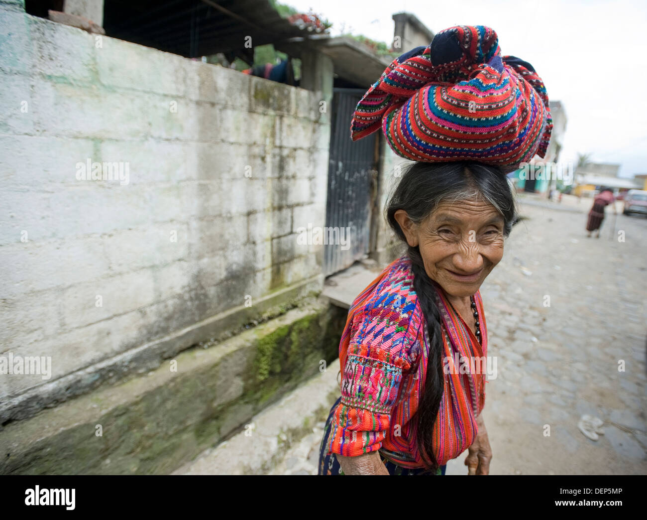 Guatemala indigenous woman of San Jorge in clothing called guipil (blouse) and corte (skirt) balancing bag on her head. Stock Photo