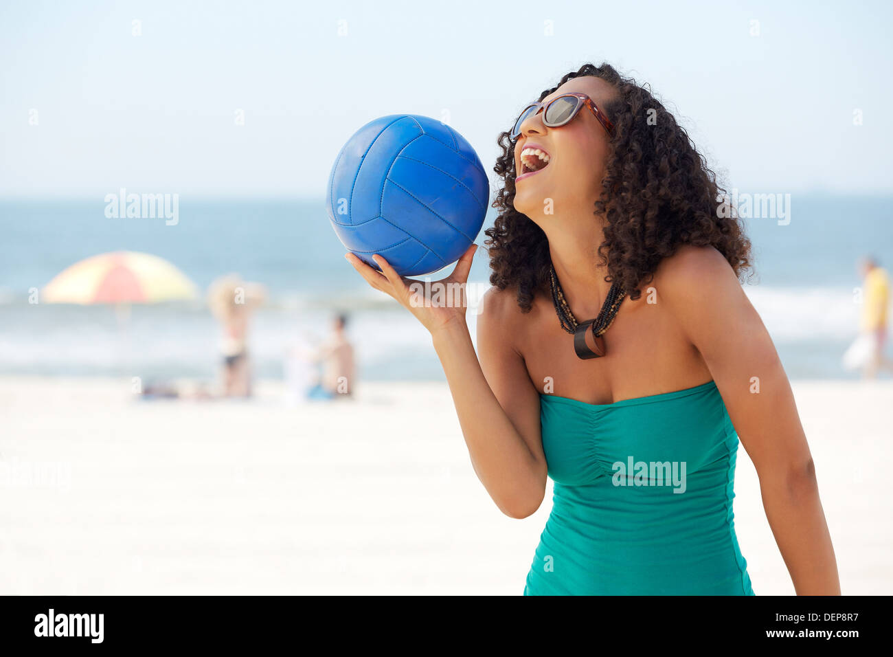Mixed race woman with volleyball on beach Stock Photo