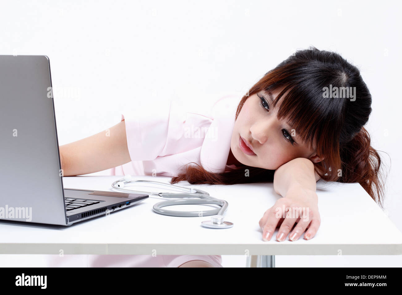 Nurse is tired of working with computer. Stock Photo