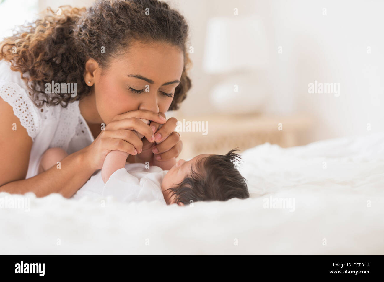 Hispanic mother playing with infant on bed Stock Photo