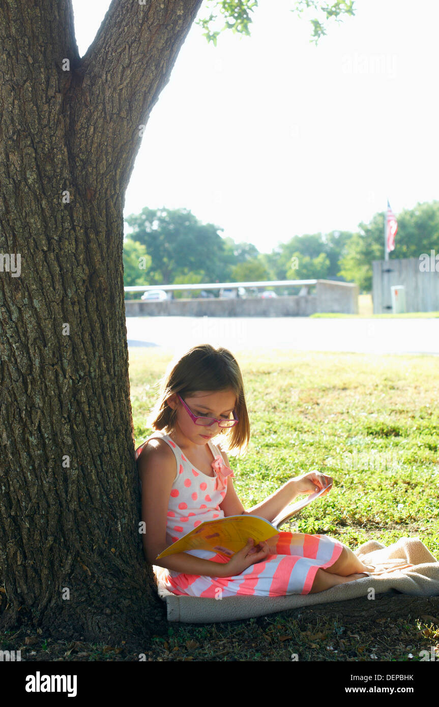 Hispanic girl reading in park Stock Photo