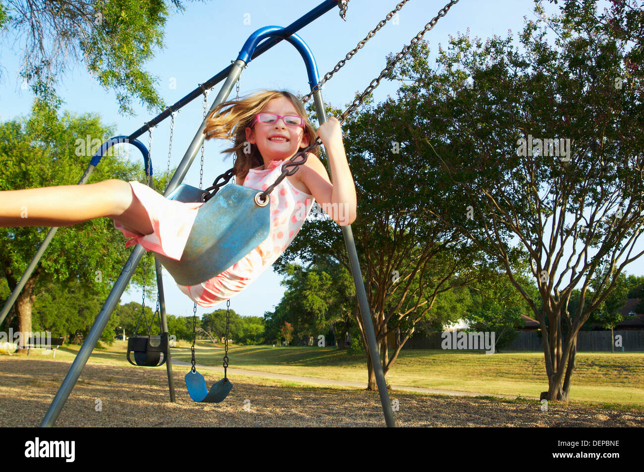 Hispanic playing on swings in park Stock Photo