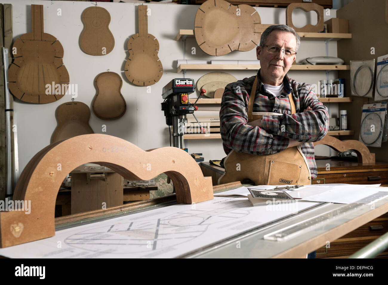 Guitar maker standing by acoustic guitar frame in portrait