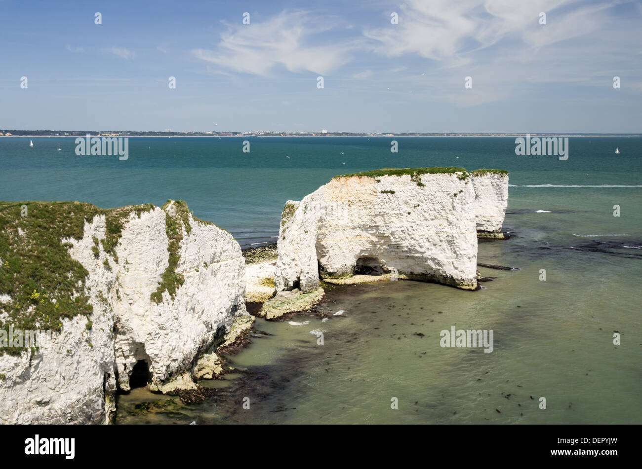 A view of white cliffs on a seashore with Bournemouth in the distance