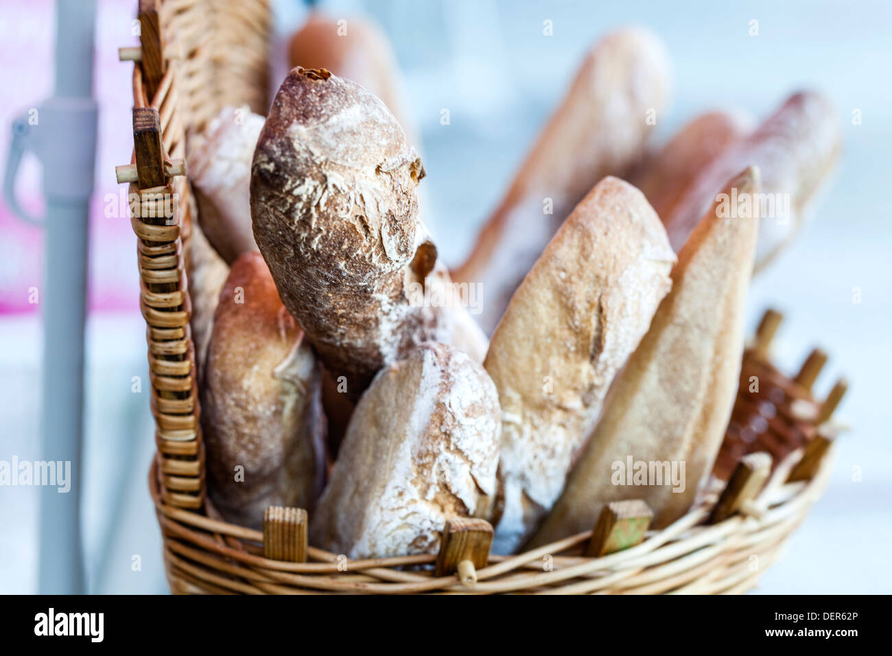 A wicker basket full of crusty fresh French bread sticks or baguettes, for sale outside a shop Stock Photo