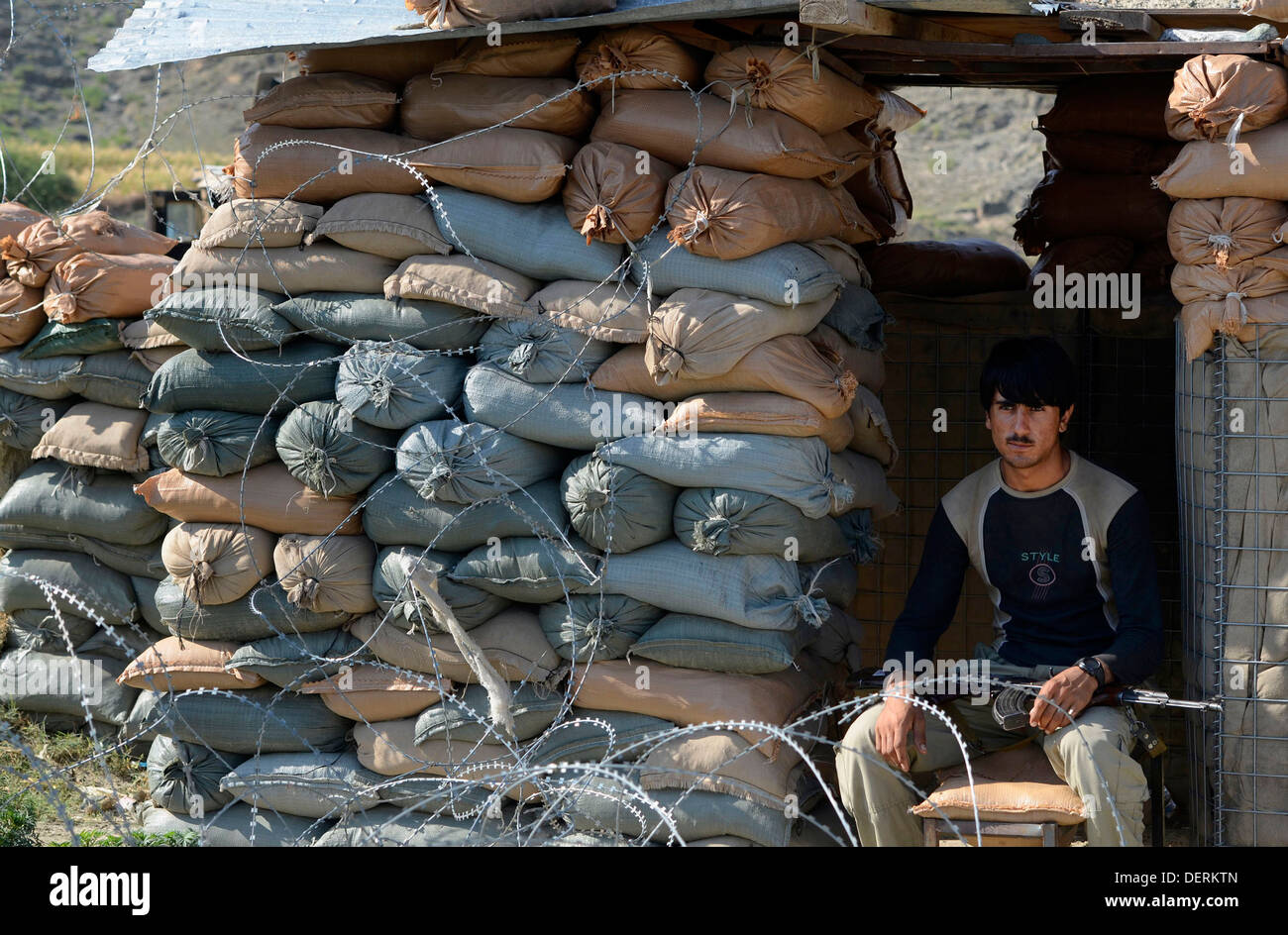 An Afghan Local Police officer sits in a bunker at a roadside checkpoint during a clearing operation September 20, 2013 in Sirkanay district, Kunar province, Afghanistan. Stock Photo