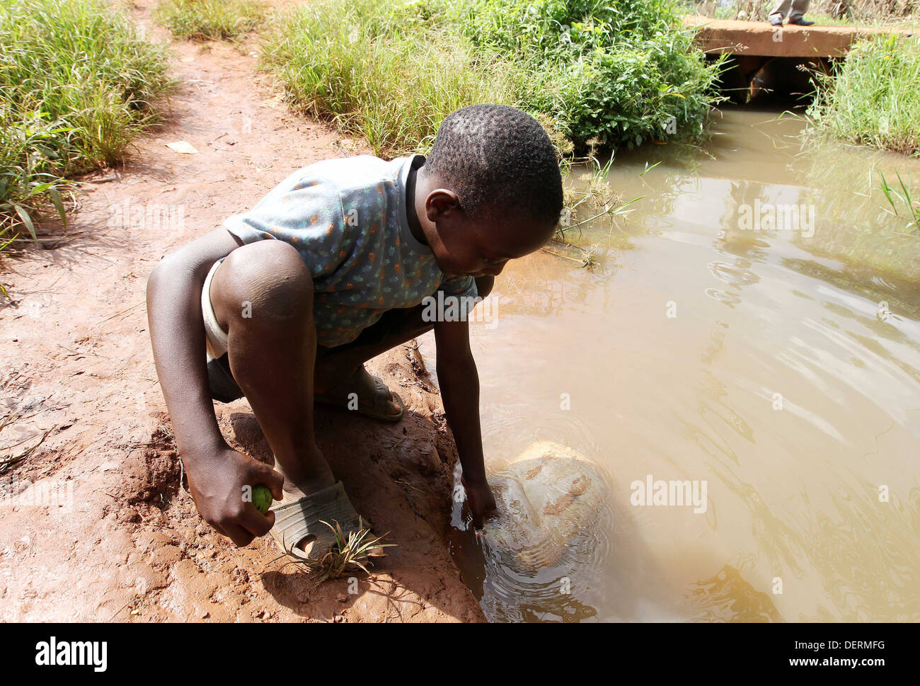 A young boy collects dirty water from a river in the Luwero district of Uganda. Stock Photo