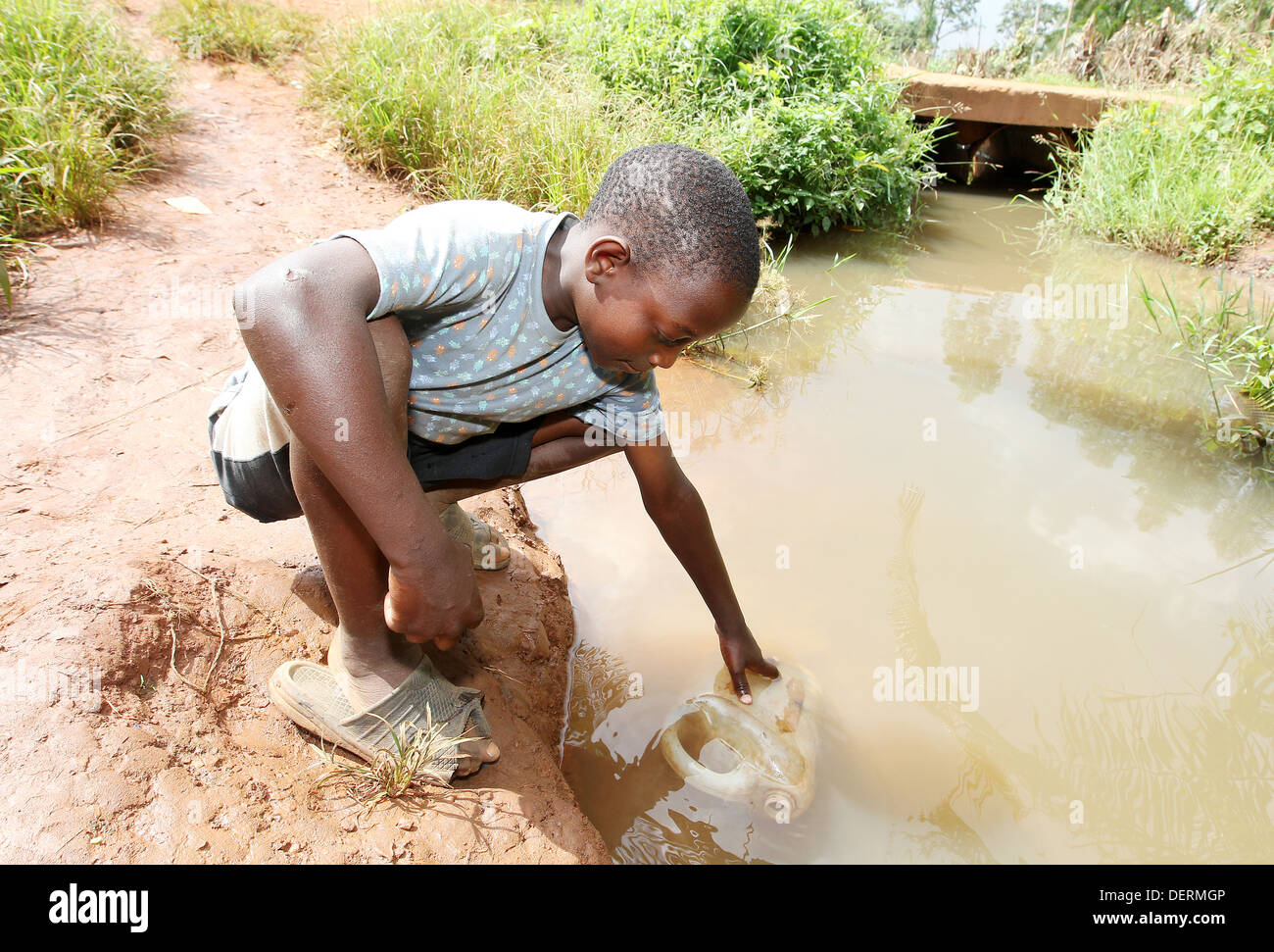 A young boy collects dirty water from a river in the Luwero district of Uganda. Stock Photo