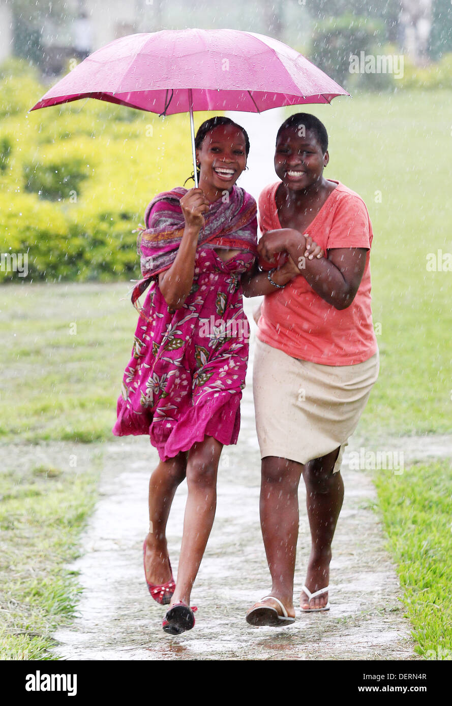 Two girls run through the rain at their high school in the Luwero district of Uganda. Stock Photo