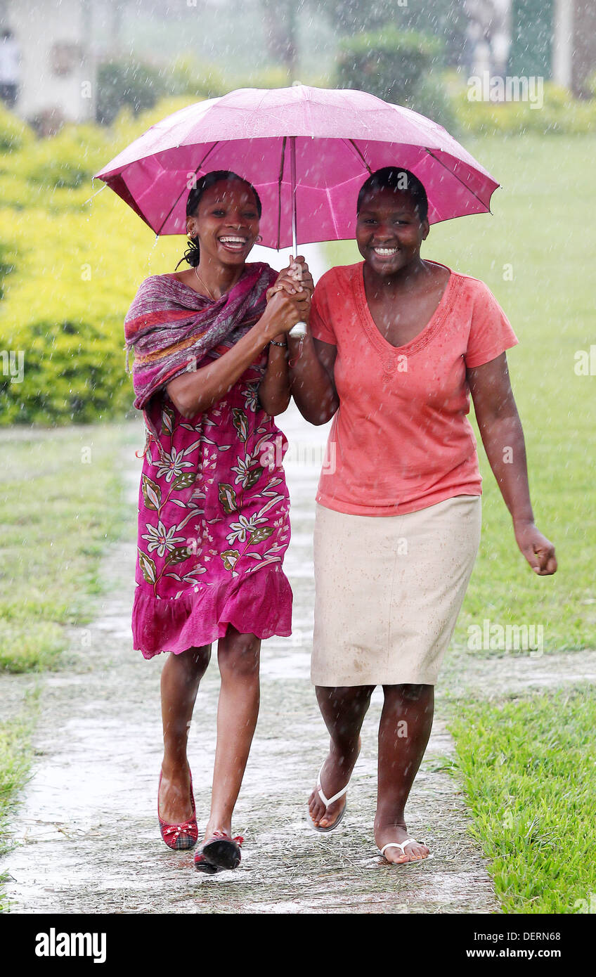 Two girls run through the rain at their high school in the Luwero district of Uganda. Stock Photo