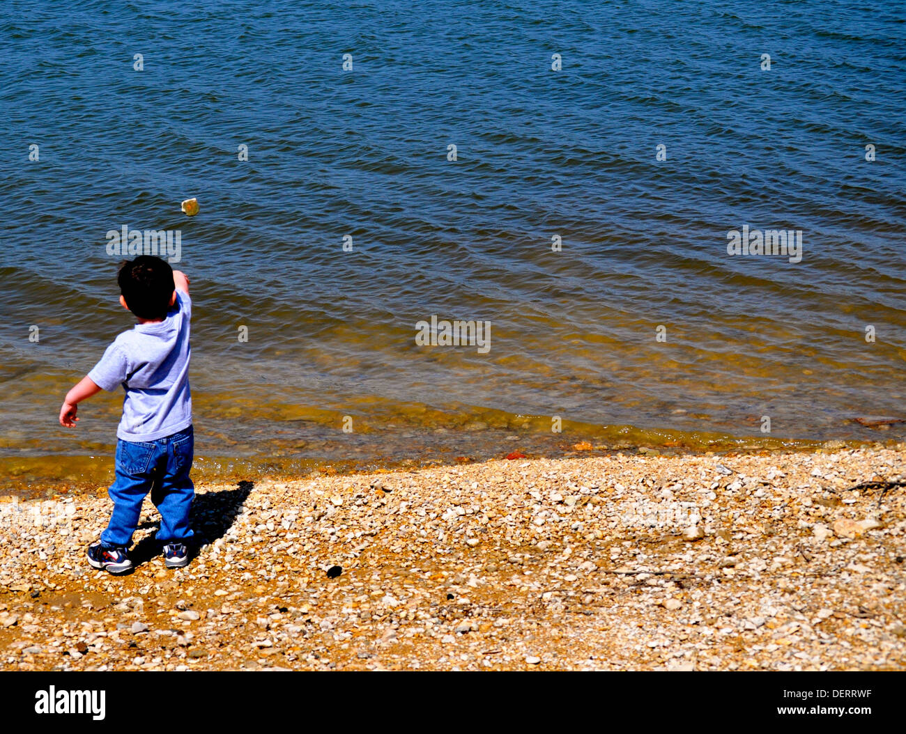 Little boy tosses the rock Stock Photo